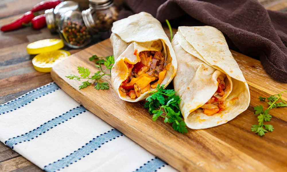 Savory chicken wraps with cheese, peppers, and herbs on a wooden board at Lahana Indian Cuisine, a Authentic Indian Cuisine Restaurant in New York