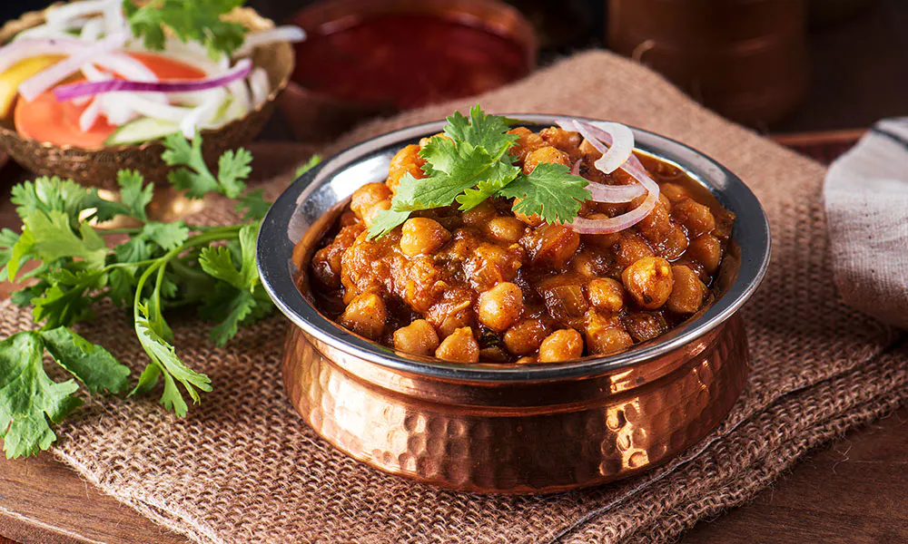 Rich chickpea curry (chana masala) garnished with cilantro and onions at Lahana Indian Cuisine, a Authentic Indian Cuisine Restaurant in New York